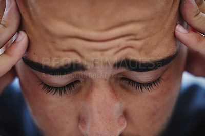 Buy stock photo Cropped shot of a young businessman sitting alone in the office and suffering from a headache