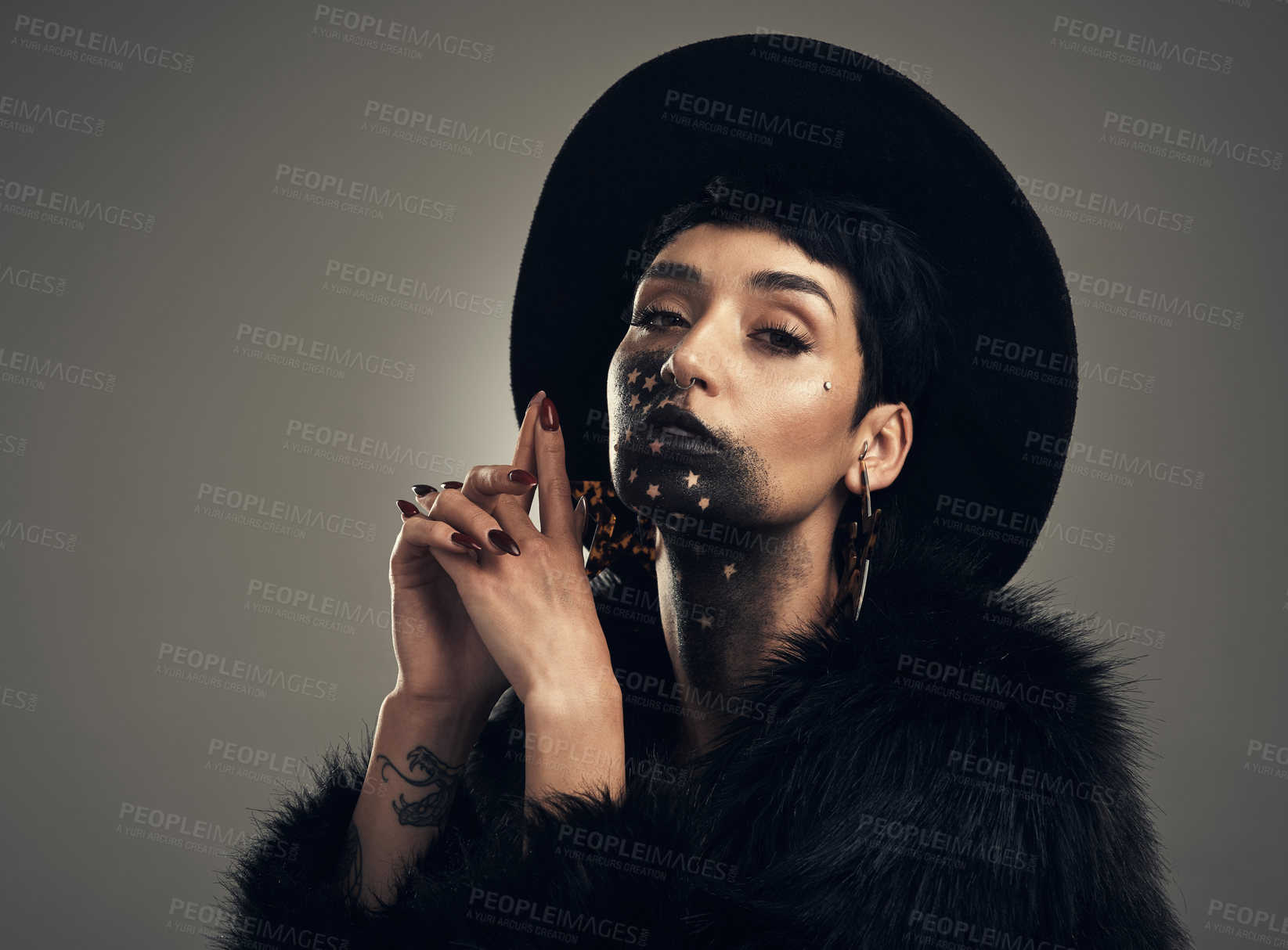 Buy stock photo Studio shot of a young woman posing with paint on her face on a grey background