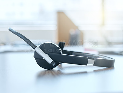 Buy stock photo Shot of a set of headsets lying on a desk in an empty office during the day
