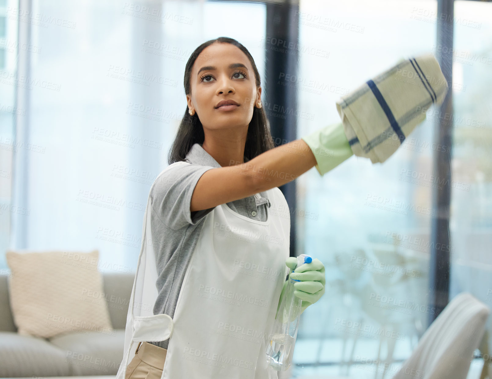 Buy stock photo Cleaning, woman and home with cloth and spray in a living room with washing glass. Young female person, maid and apron in a house for housekeeping and cleaner with disinfect and scrub by window