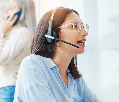 Buy stock photo Shot of an attractive young saleswoman sitting in the office and wearing a headset