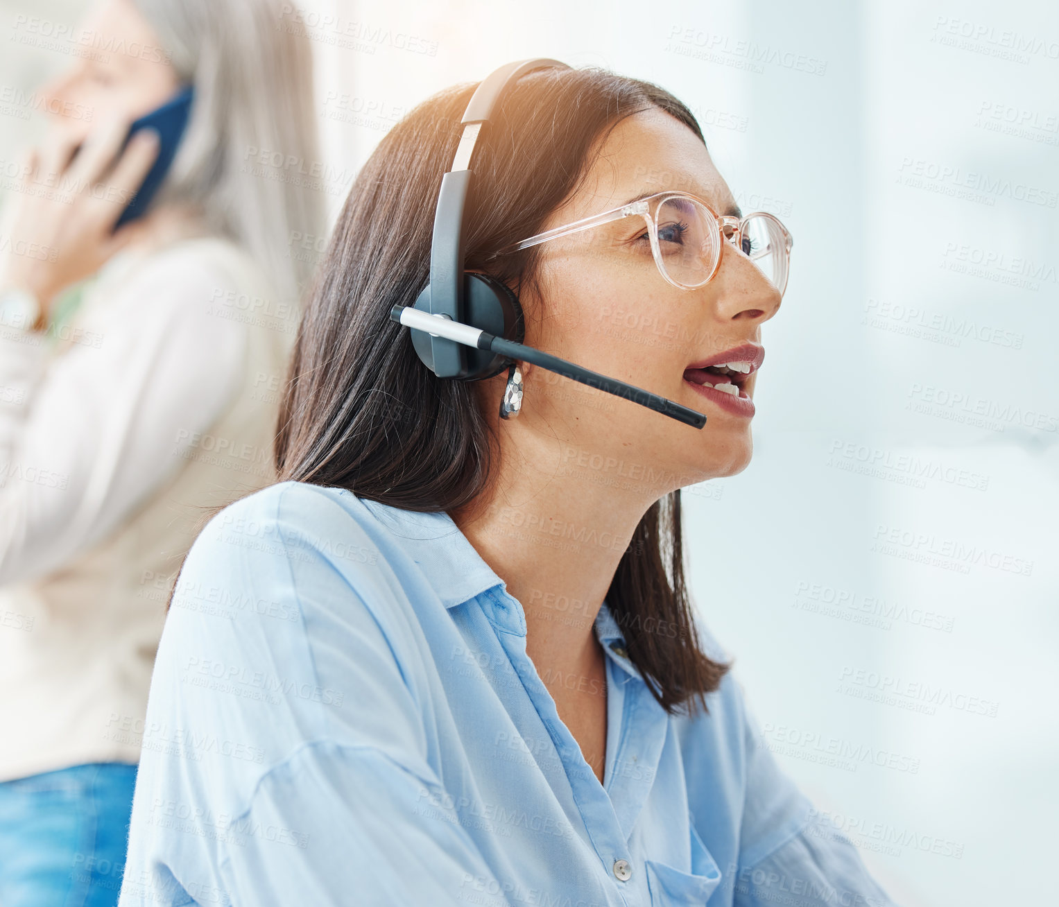 Buy stock photo Shot of an attractive young saleswoman sitting in the office and wearing a headset