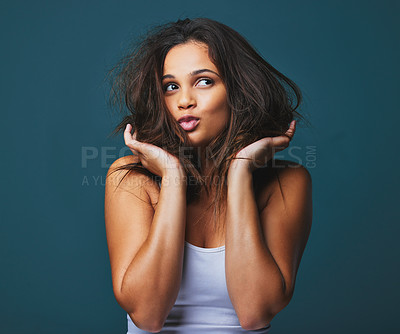 Buy stock photo Studio shot of a beautiful young woman lifting her hair with her hands posing against a blue background