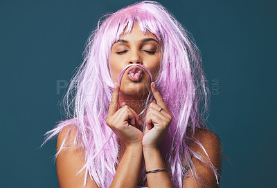 Buy stock photo Studio shot of a beautiful young woman posing with a playful pink wig against a blue background