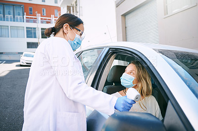 Buy stock photo Shot of a masked young woman getting her temperature checked by a doctor while sitting in her car