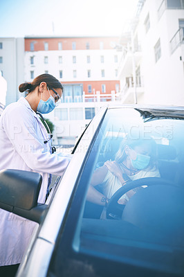 Buy stock photo Shot of a masked young doctor giving a patient an injection at a Covid-19 drive through testing centre