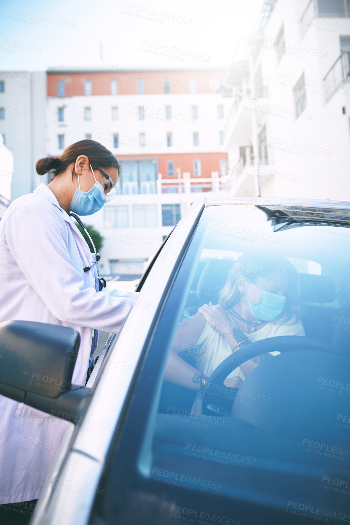 Buy stock photo Shot of a masked young doctor giving a patient an injection at a Covid-19 drive through testing centre