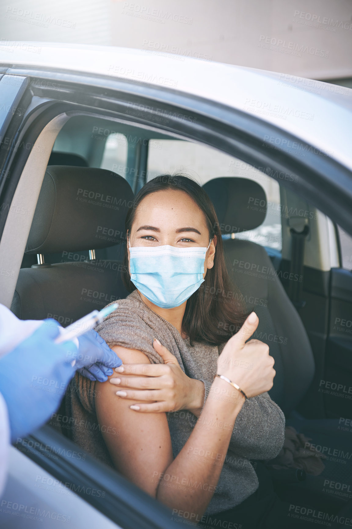 Buy stock photo Shot of a masked young woman receiving an injection at a Covid-19 drive through testing centre