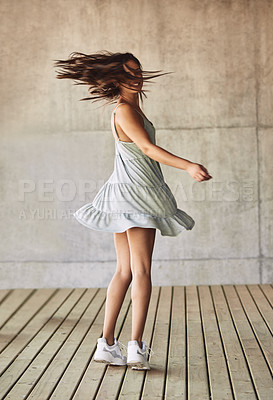 Buy stock photo Shot of a young woman twirling in a dress against an urban background