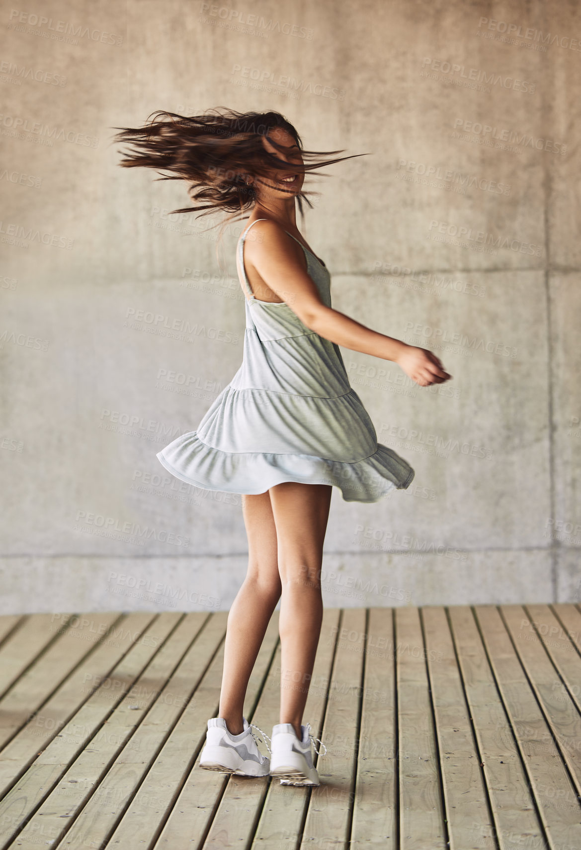 Buy stock photo Shot of a young woman twirling in a dress against an urban background