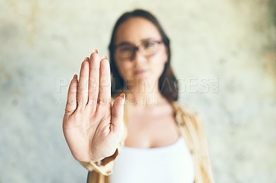 Buy stock photo Portrait of a woman holding up her hand while standing against a wall