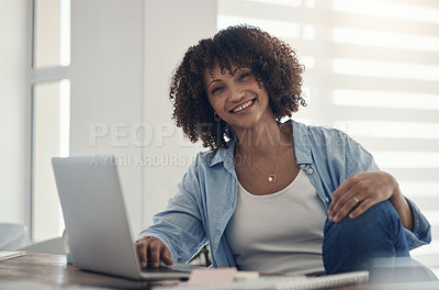 Buy stock photo Shot of an attractive young woman sitting alone at home and using her laptop