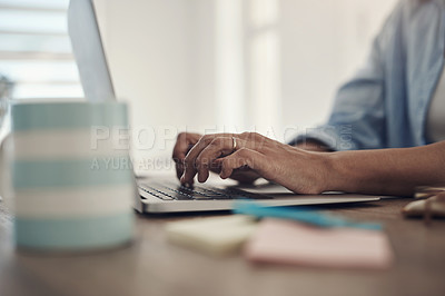 Buy stock photo Cropped shot of an unrecognizable woman sitting alone at home and using her laptop