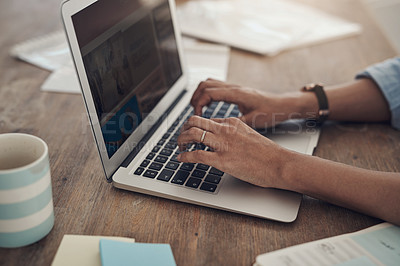 Buy stock photo Cropped shot of an unrecognizable woman sitting alone at home and using her laptop