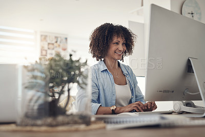 Buy stock photo Shot of an attractive young woman sitting alone at home and using her computer