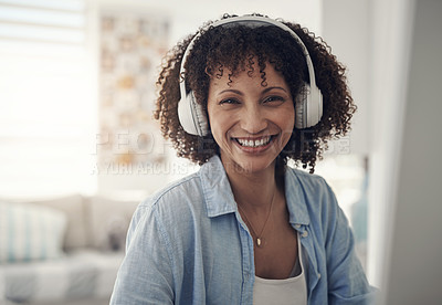 Buy stock photo Shot of an attractive young woman sitting alone at home and wearing headphones