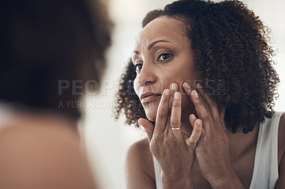 Buy stock photo Shot of an attractive young woman standing in her bathroom at home and using a mirror to check her skin