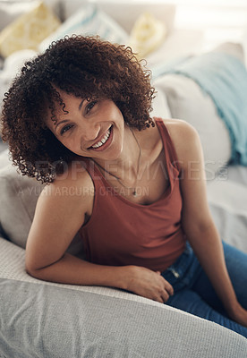 Buy stock photo Shot of an attractive young woman sitting alone on her sofa in the living room at home