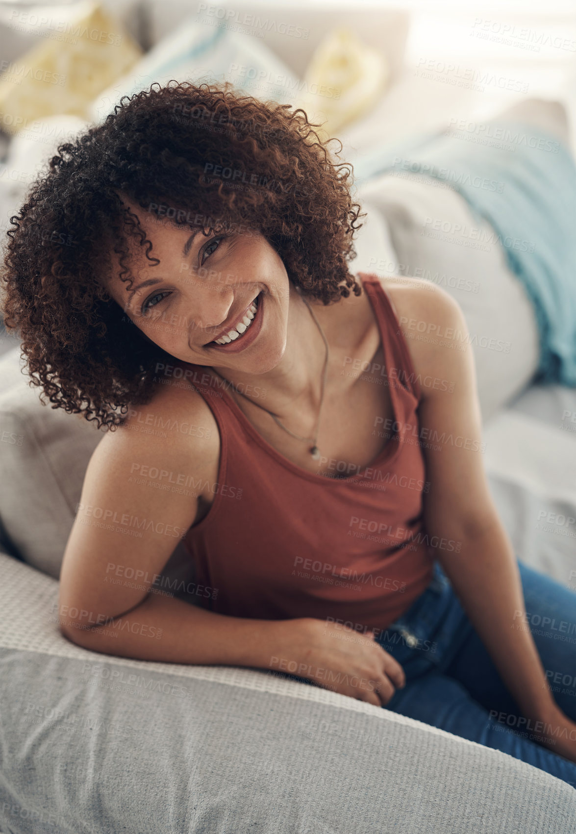 Buy stock photo Shot of an attractive young woman sitting alone on her sofa in the living room at home