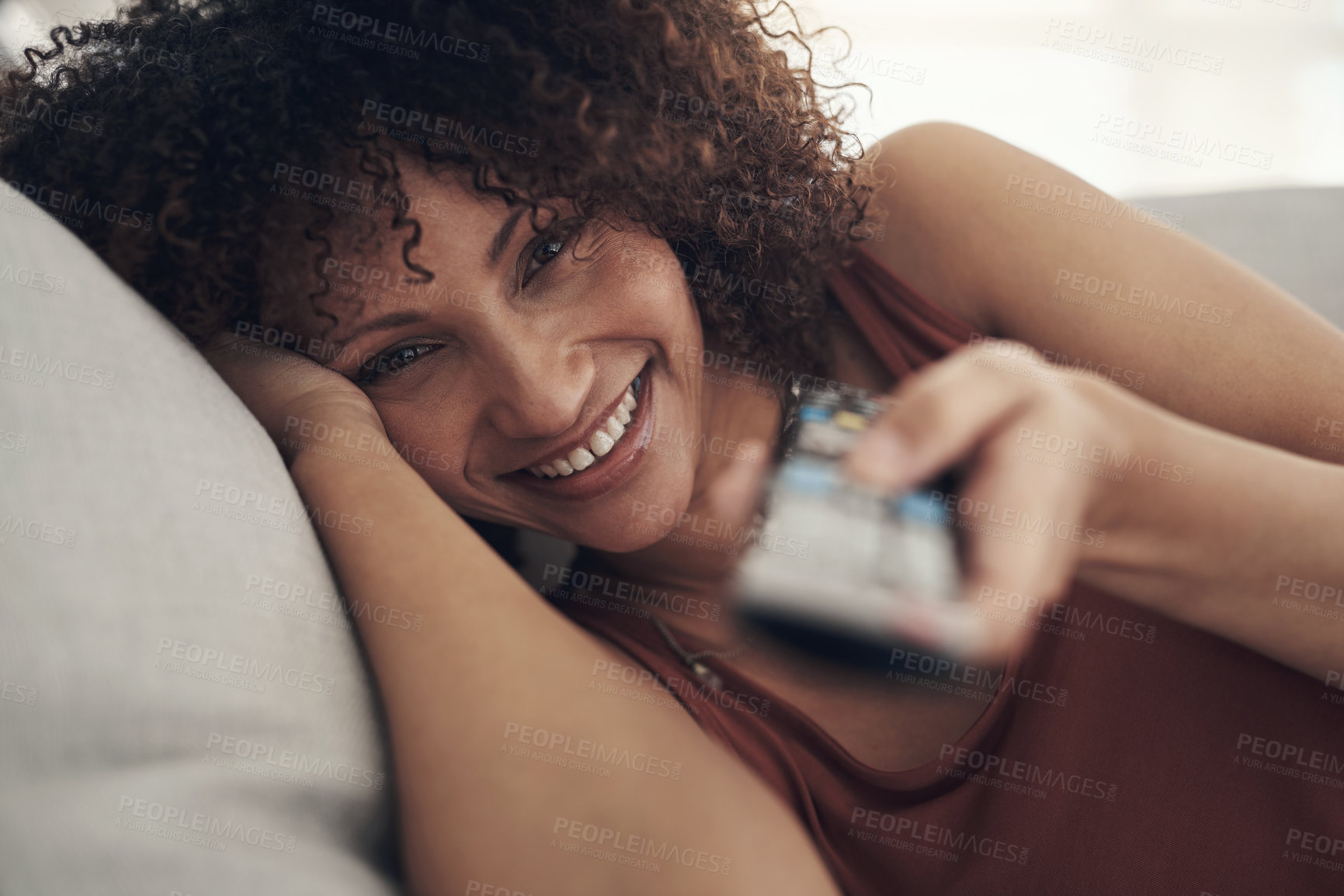 Buy stock photo Shot of an attractive young woman relaxing on the sofa in the living room at home and watching tv