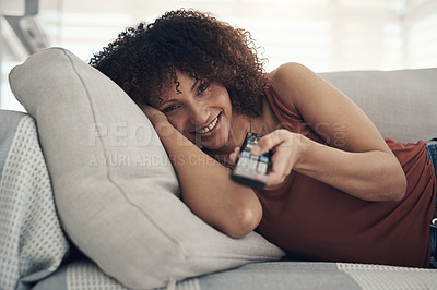 Buy stock photo Shot of an attractive young woman relaxing on the sofa in the living room at home and watching tv