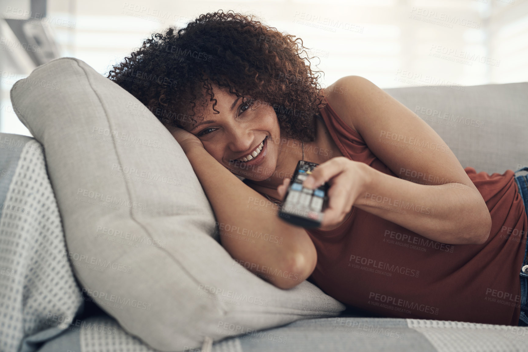 Buy stock photo Shot of an attractive young woman relaxing on the sofa in the living room at home and watching tv