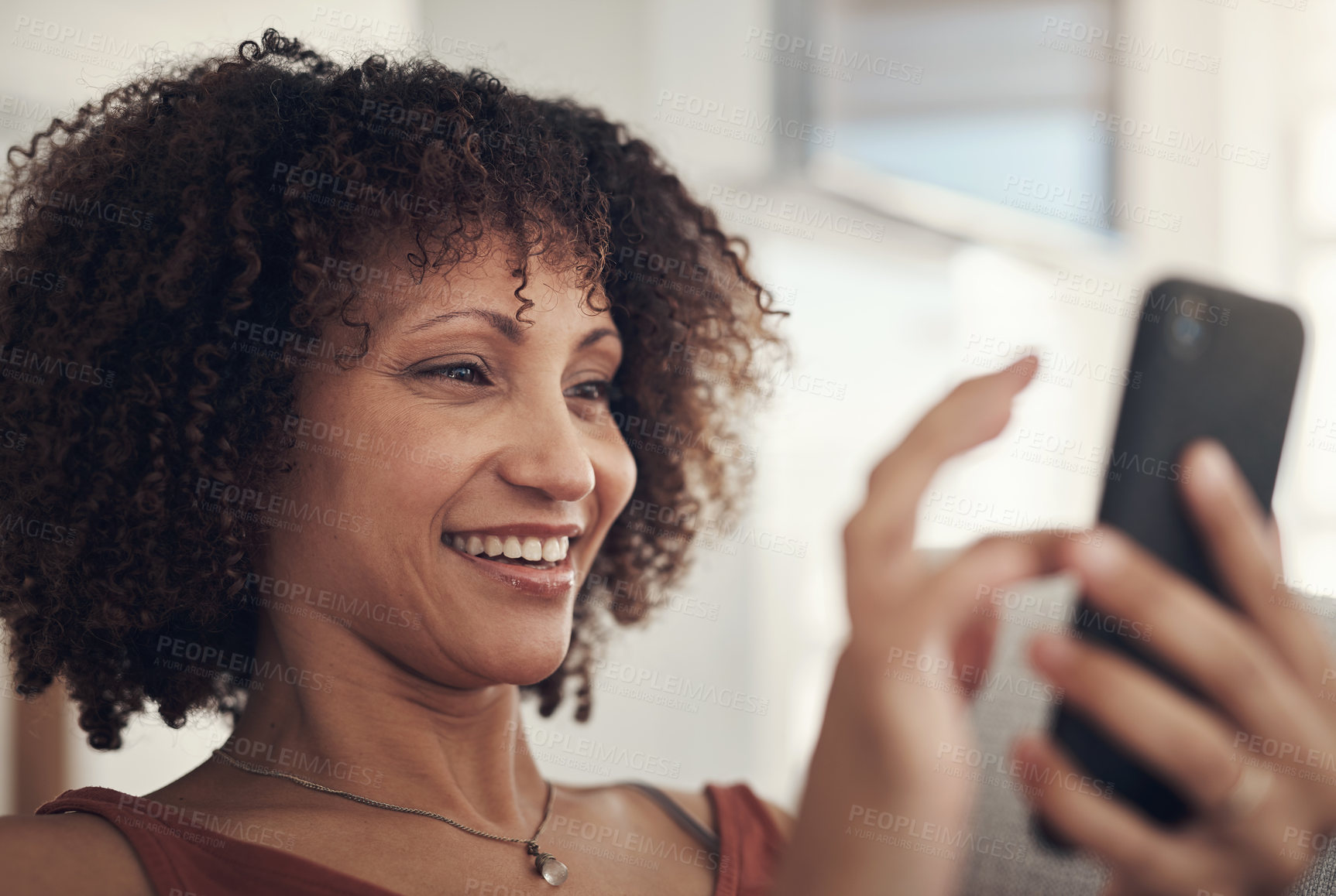 Buy stock photo Shot of an attractive young woman sitting on her sofa in the living room at home and using her cellphone