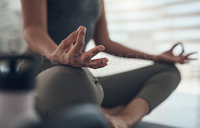 Buy stock photo Cropped shot of an unrecognizable woman sitting alone in her living room and meditating