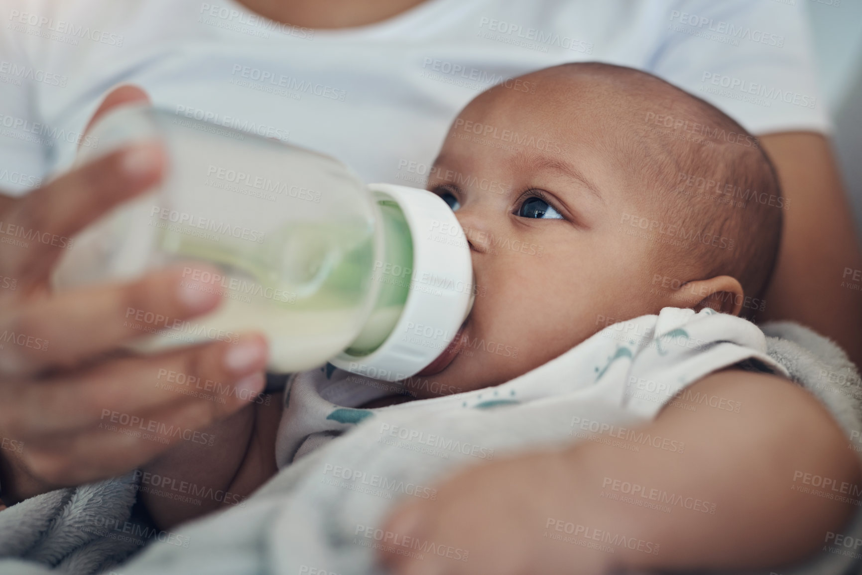 Buy stock photo Shot of an adorable baby girl being bottle fed by her mother on the sofa at home