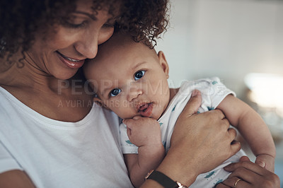 Buy stock photo Shot of a young woman carrying her adorable baby girl at home