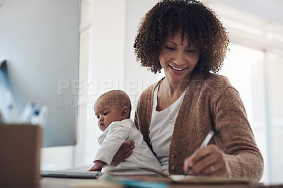 Buy stock photo Shot of a young woman making notes while caring for her adorable baby girl and working at home