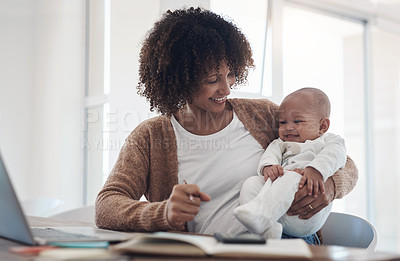 Buy stock photo Shot of a young woman using a laptop while caring for her adorable baby girl at home