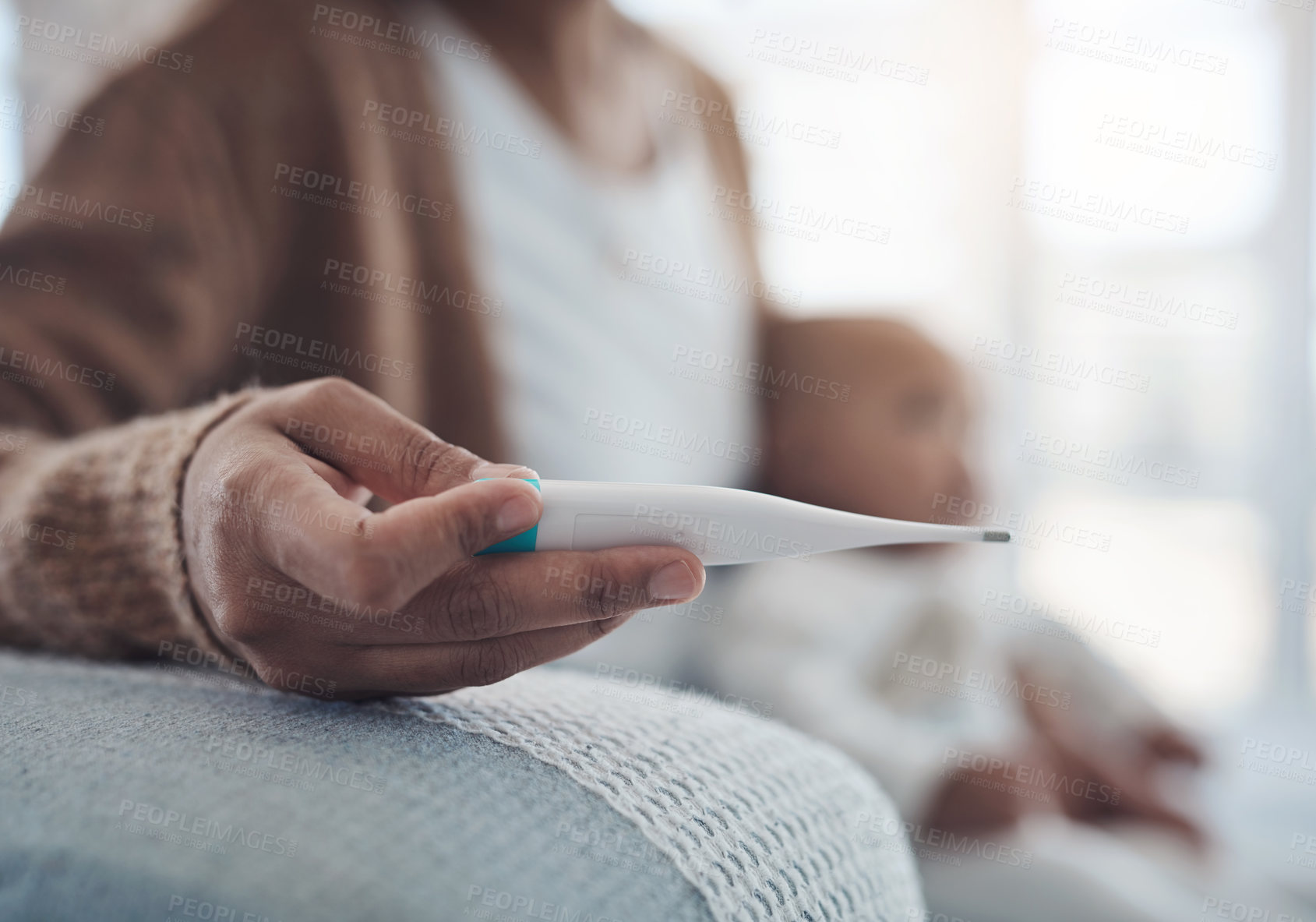 Buy stock photo Shot of a woman checking her baby’s temperature with a thermometer on the sofa at home