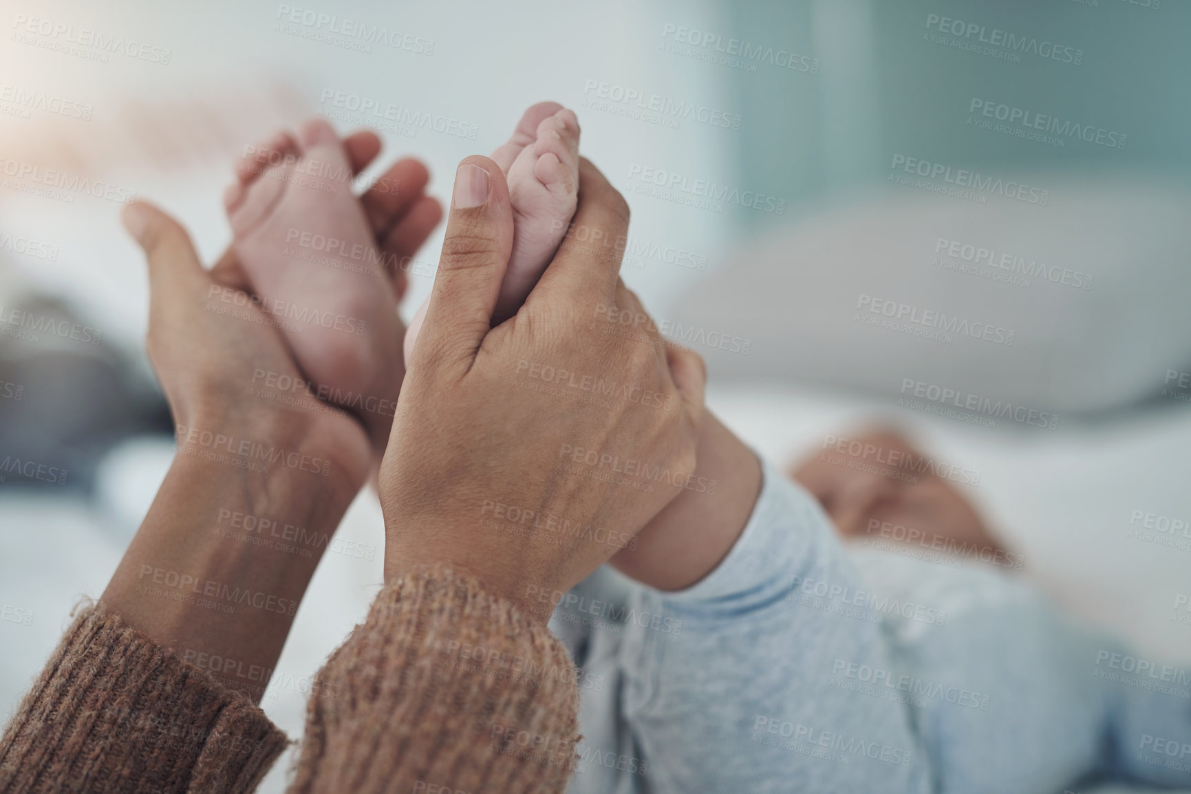 Buy stock photo Shot of an unrecognisable woman holding her baby’s feet on the bed at home