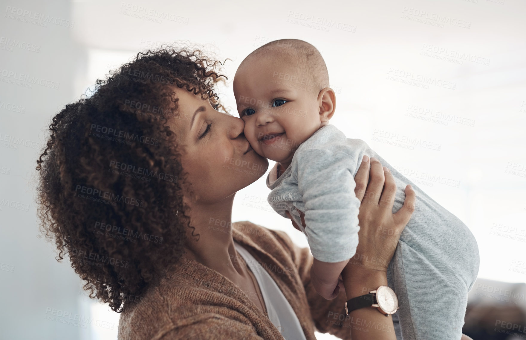 Buy stock photo Shot of a young woman kissing her adorable baby girl at home