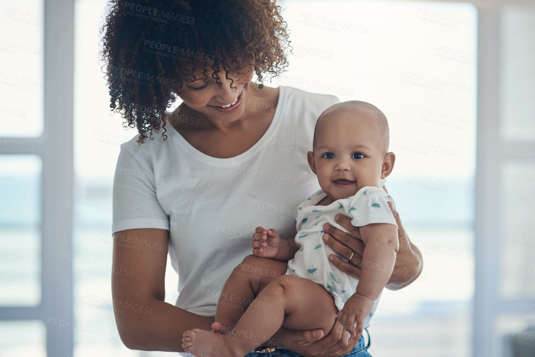 Buy stock photo Shot of a young woman carrying her adorable baby girl at home