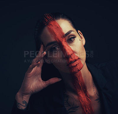 Buy stock photo Studio shot of a young woman posing with paint on her face on a black background