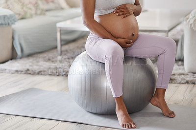 Buy stock photo Cropped shot of a pregnant woman sitting on a stability ball at home