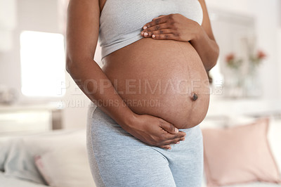 Buy stock photo Closeup shot of an unrecognisable woman touching her pregnant belly at home
