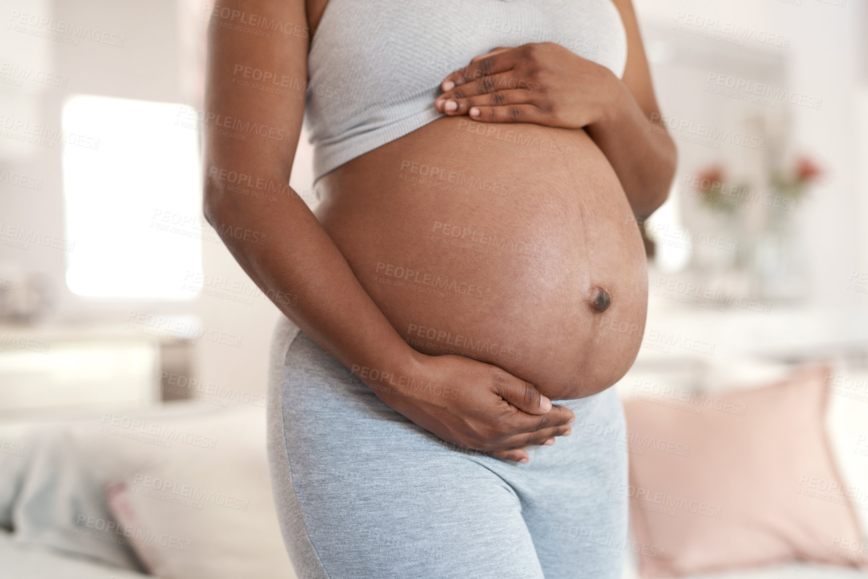 Buy stock photo Closeup shot of an unrecognisable woman touching her pregnant belly at home