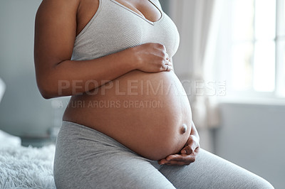 Buy stock photo Closeup shot of an unrecognisable woman touching her pregnant belly at home