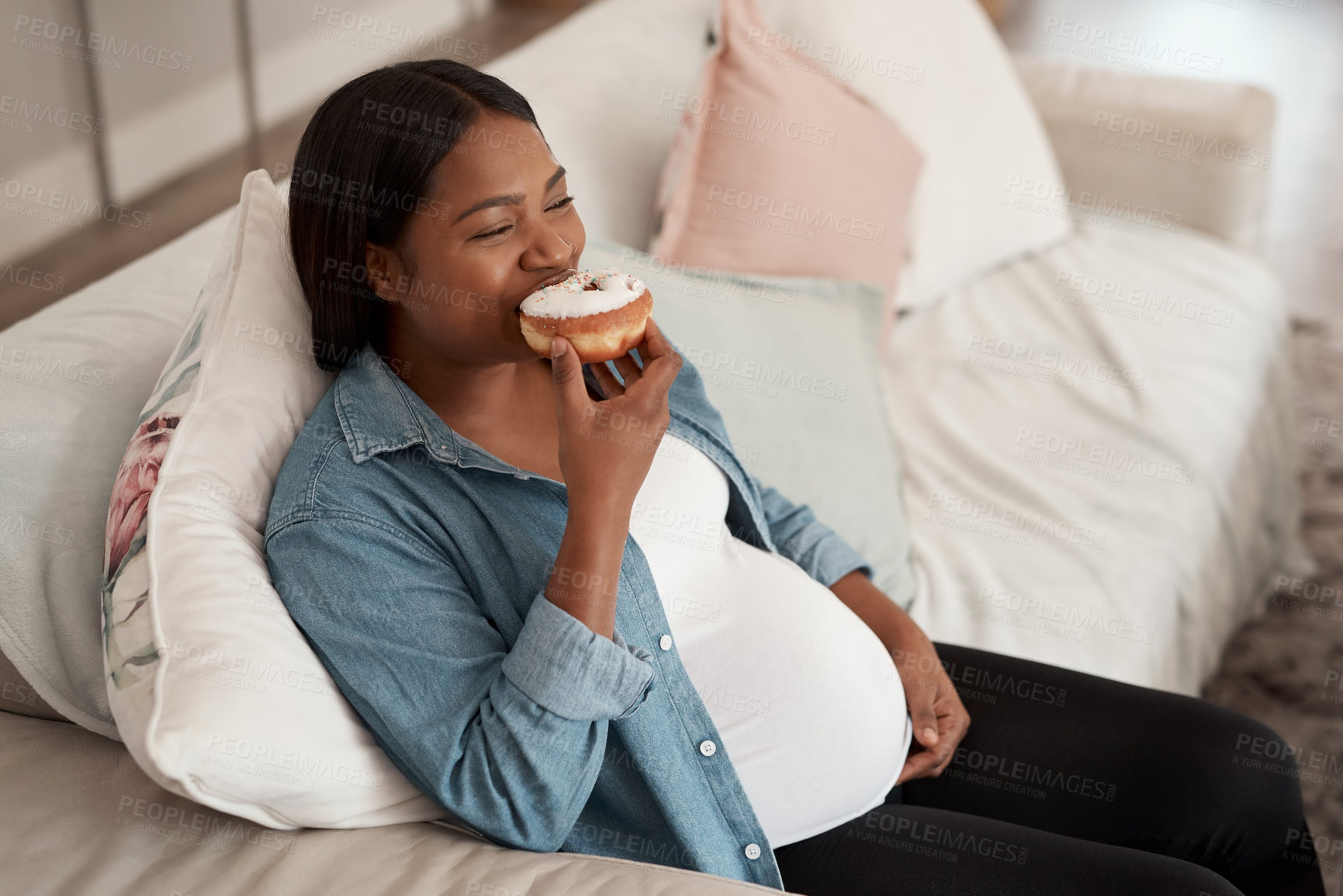 Buy stock photo Shot of a pregnant woman eating a donut at home