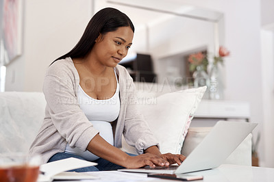 Buy stock photo Shot of a pregnant woman working on her laptop while sitting at home