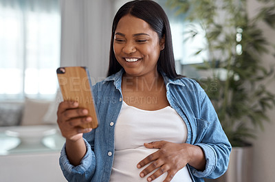 Buy stock photo Shot of a pregnant woman using her cellphone while sitting at home