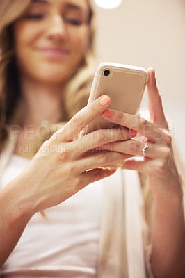 Buy stock photo Shot of a young woman using her smartphone in a clothing store