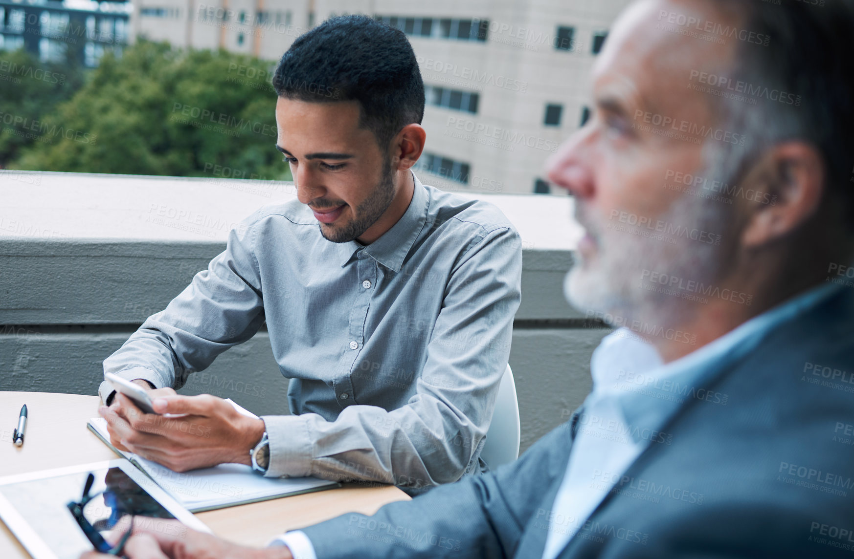 Buy stock photo Business man, smartphone and rooftop meeting for communication, teamwork and collaboration. Male person, mobile tech and talking to coworkers or partners for start up, deal negotiation and planning