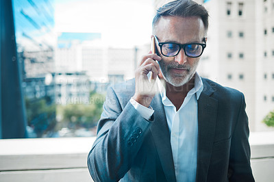 Buy stock photo Shot a mature businessman using a phone against an urban background