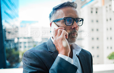 Buy stock photo Shot a mature businessman using a phone against an urban background