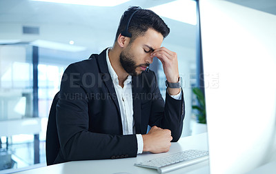 Buy stock photo Shot of a young businessman experiencing a headache at his desk