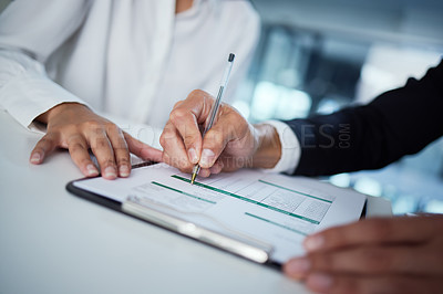 Buy stock photo Shot of two business colleagues filling out paperwork in the office